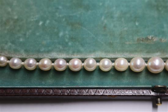 A single strand graduated cultured pearl necklace with an emerald and diamond set white metal clasp, approx. 35cm.